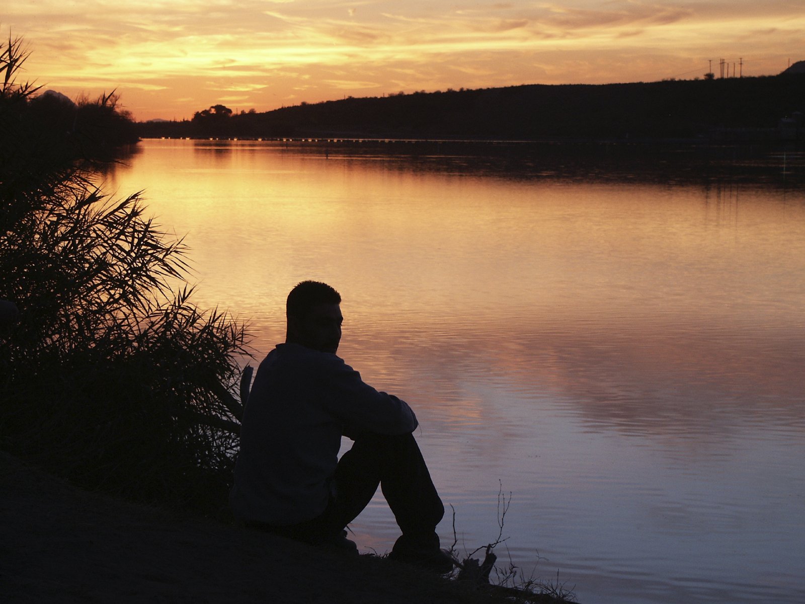 Мужчина сидит на берегу реки